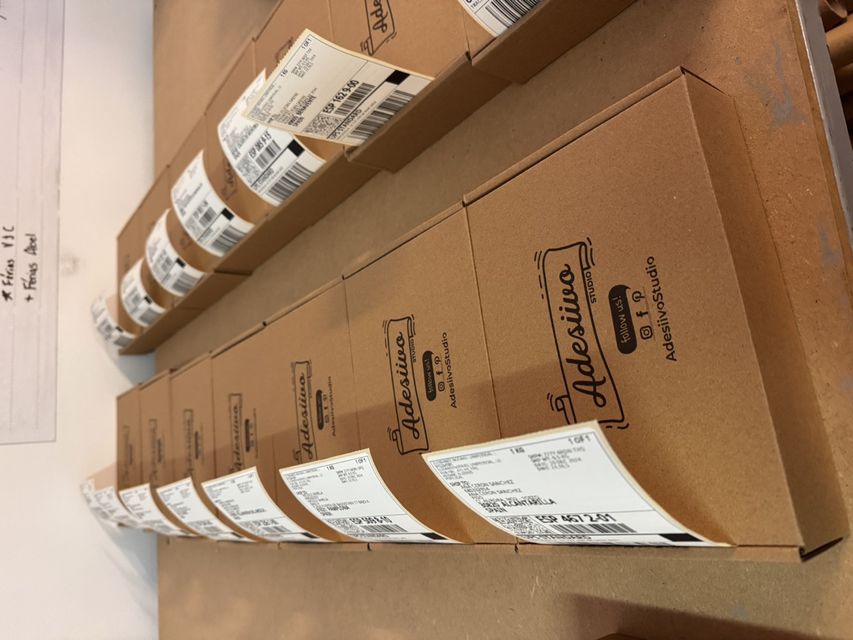 Cajas de la marca AdesiivoStudio listas para envío
